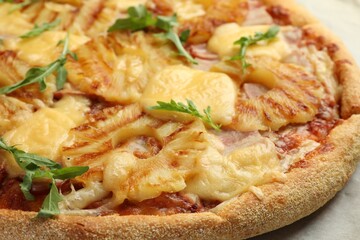 Delicious pineapple pizza with arugula on table, closeup