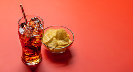 Refreshing glass of cola with ice, accompanied by a serving of crispy chips
