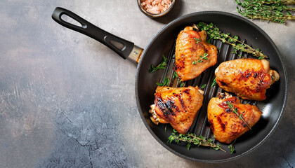 grilled chicken thighs in a frying pan with fresh thyme, view from above, flatlay, empty space