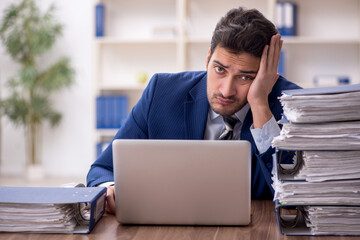 Young male employee and too much work in the office