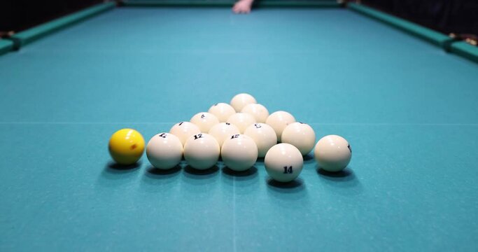 White billiard balls triangle on table. Hitting balls with yellow ball to start game