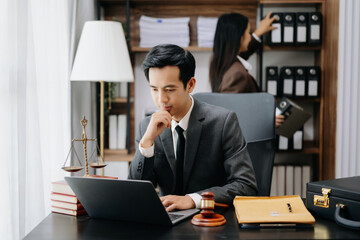 Asian lawyer man working with a laptop and tablet in a law office. Legal and legal service concept. Looking at camera in modern office.