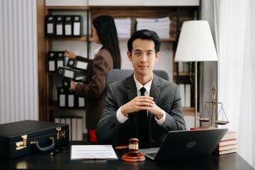 Asian lawyer man working with a laptop and tablet in a law office. Legal and legal service concept. Looking at camera in modern office.