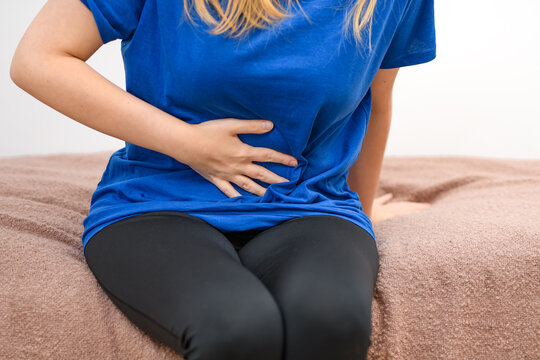 Młoda kobieta trzyma się za brzuch 