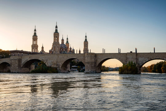 Arched bridge over river at sunset
