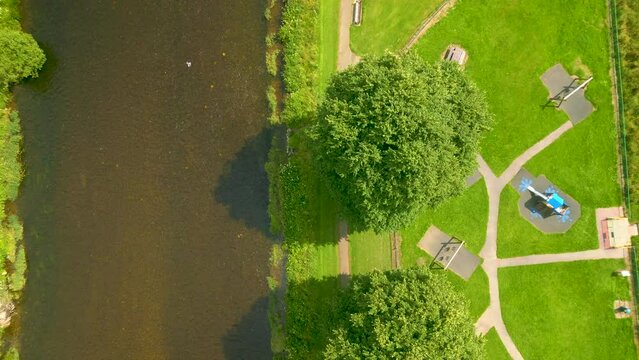 Aerial Drone shot overflying a river beside a park with trees