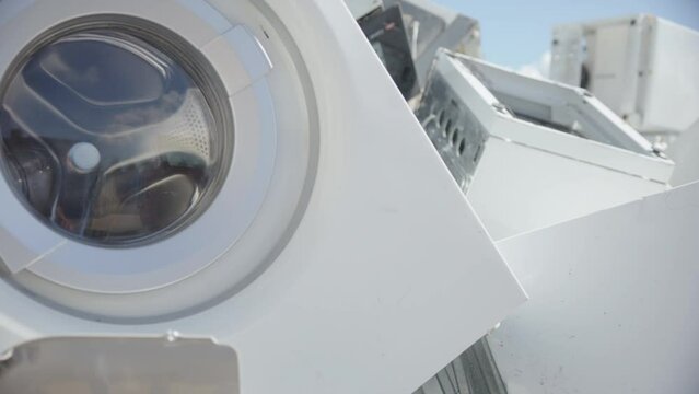 Discarded household washing machines and e-waste at disposal center, closeup