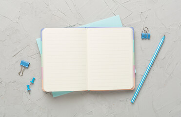 Open notebook with stationery on concrete background, top view