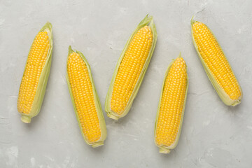 Fresh corn on cobs on concrete background, top view