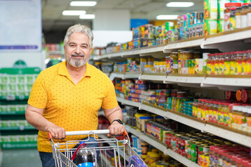 Senior indian man purchasing at grocery shop.