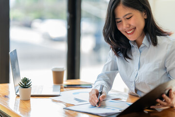 young asian businesswomen sit desks and calculate financial graphs showing results about investments, plan a successful business growth process