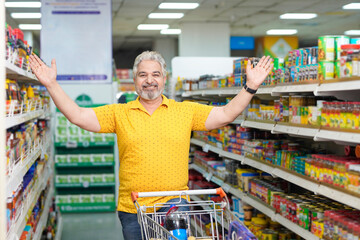 Senior indian man giving expression while purchasing at grocery shop.