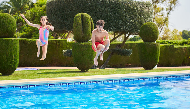 Cheerful preteen in swimsuit jumping into pool
