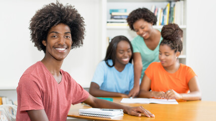 Laughing black male student at desk with group of learning african american students