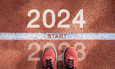 New year 2024 concept, beginning of success. Text 2024 written on asphalt road and male runner preparing for the new year. Concept of challenge or career path and change. - obrazy, fototapety, plakaty