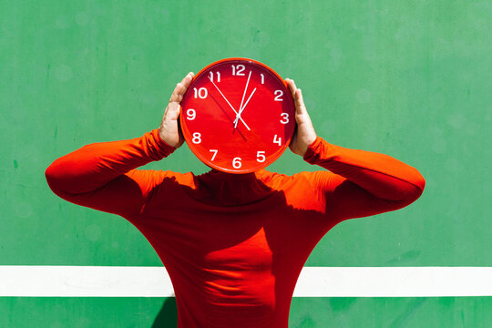 Anonymous person covering face with red clock