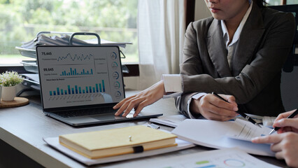 Closeup hand of Chief and employee discuss monthly earning graph together in the office