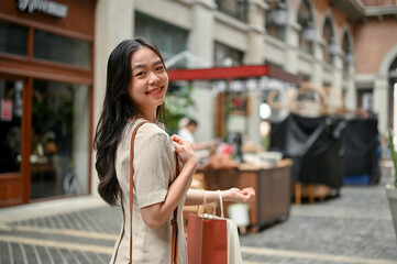 An attractive Asian female enjoying her shopping day in the city market on the weekend.