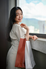 A beautiful Asian female tourist with her shopping bags looking at the city view from a city tower