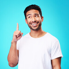 Fototapeta premium Mockup, pointing up and man with a smile, thinking and solution against a blue studio background. Male person, decision and model with hand gesture, opportunity or option with sign, choice or showing