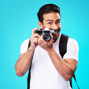 Portrait, creativity and man with a camera, photography and artist against a blue studio background. Face, male person and model with vintage technology, journalist and photographer with inspiration