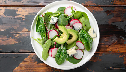 gorgonzola,avocado, spinach, european radish low carb delicious salad on white platter on old dark wooden table, view from above