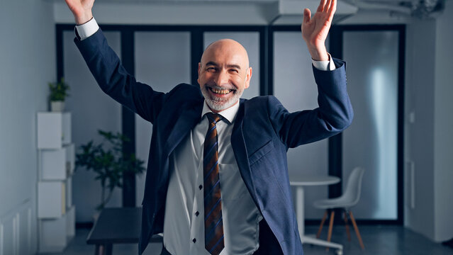 Dancing middle-aged white man in a suit in the office. Facial expression.