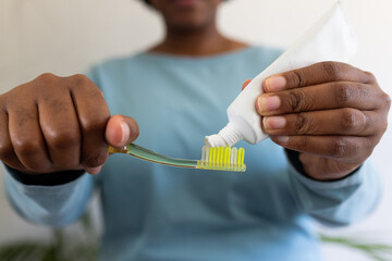 Hands of plus size african american woman putting toothpaste on toothbrush