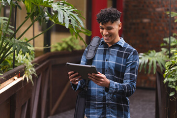 Biracial man smiling while using a digital tablet at office