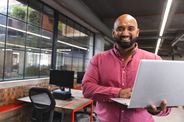 Portrait of indian man with a laptop smiling at office