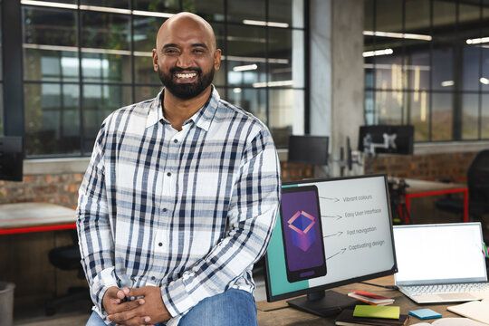 Portrait of indian man smiling while sitting at modern office