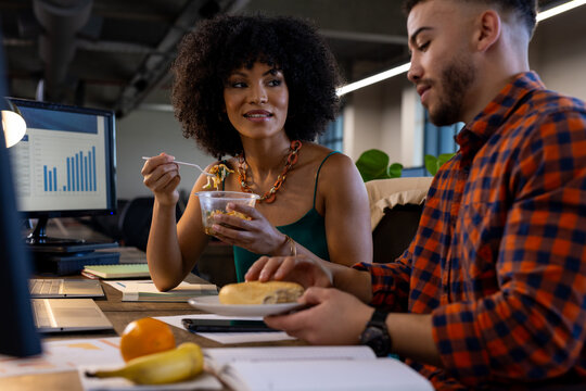 Happy diverse man and woman having snacks together at office