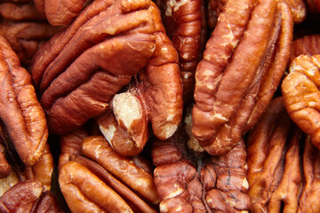 Pecan nuts kernel texture background closeup. Heap of peeled pecan halves. The closeup portrays pecans nutty allure