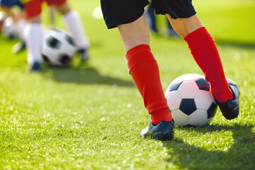 Close-up of legs and feet of football player in red socks and shoes running and dribbling with the...