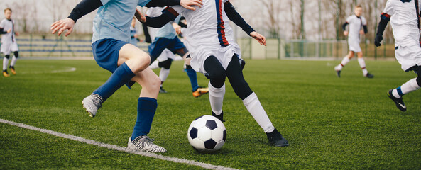 Legs of two young football players on a match. Two soccer players running and kicking a soccer...