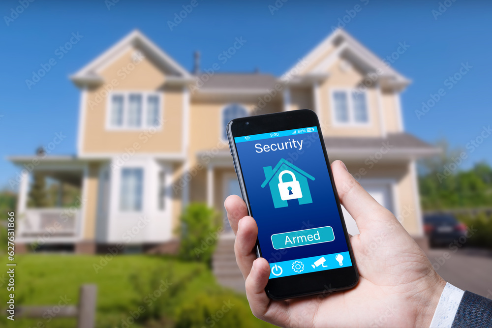 Poster smartphone with home security app in a hand on the building background.