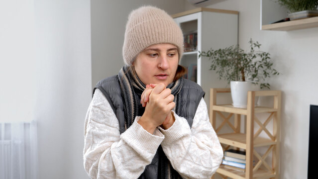 Portrait of woman in warm clothes shivering and dancing in cold house. Concept of energy crisis, high bills, economy