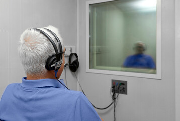 Audiologist woman doing the hearing exam to a mixed race man patient using an audiometer in a special audio room. Audiometric testing. Hearing loss treatment.