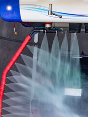 action. Car going through an automated wash. High-pressure water spray in the wash machine. Dotted...