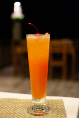 Fresh orange cocktail with ice and cherry standing on the table, alcoholic beverages
