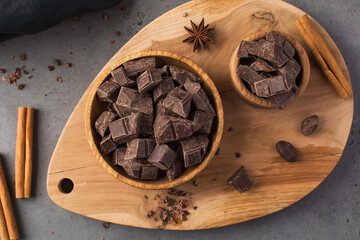 Cubes of dark artisan chocolate in a wooden bowl. Bitter chocolate