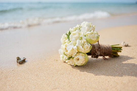 Beautiful bridal bouquet of white lotuses and orchids on a tropical beach.
