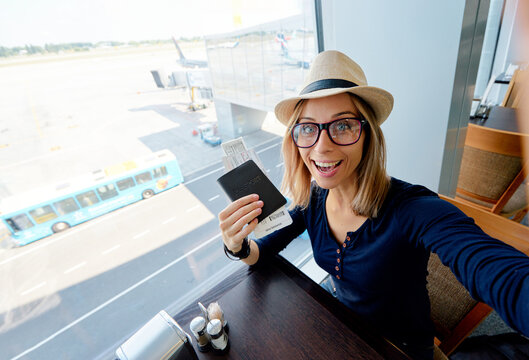 Enjoy traveling! Vacation Selfie. Beautiful young woman in hat taking selfie while waiting for boarding in the airport.