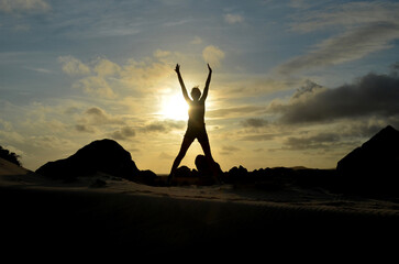 Woman with Arms Raised Silhouetted at Sunrise