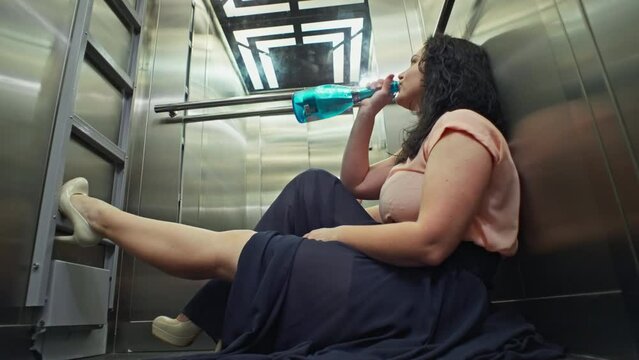 Caucasian female girl with bottle of champagne riding in elevator after party. A drunk woman returns home. High quality 4k footage