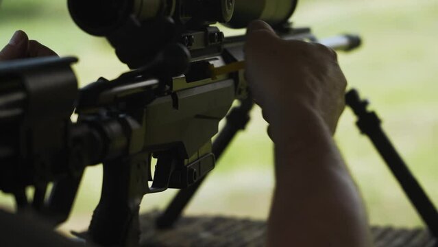 The shooter inserts a clip with cartridges into a sniper rifle. Close-up