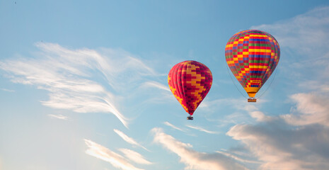 Colorful hot air balloon flying over clouds at sunset