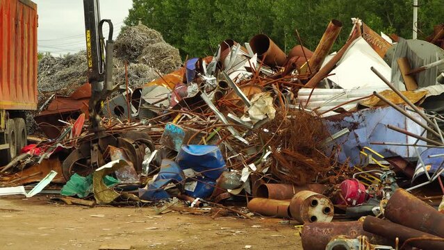The concept of recycling secondary resources, metal. Hydraulic manipulator, loads scrap metal into the truck body.