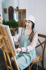 Young female artist painting on canvas in the home studio, fine arts and creativity concept.