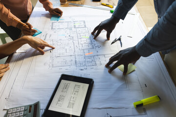 Diverse colleagues discussing work with tablet over project of building in office